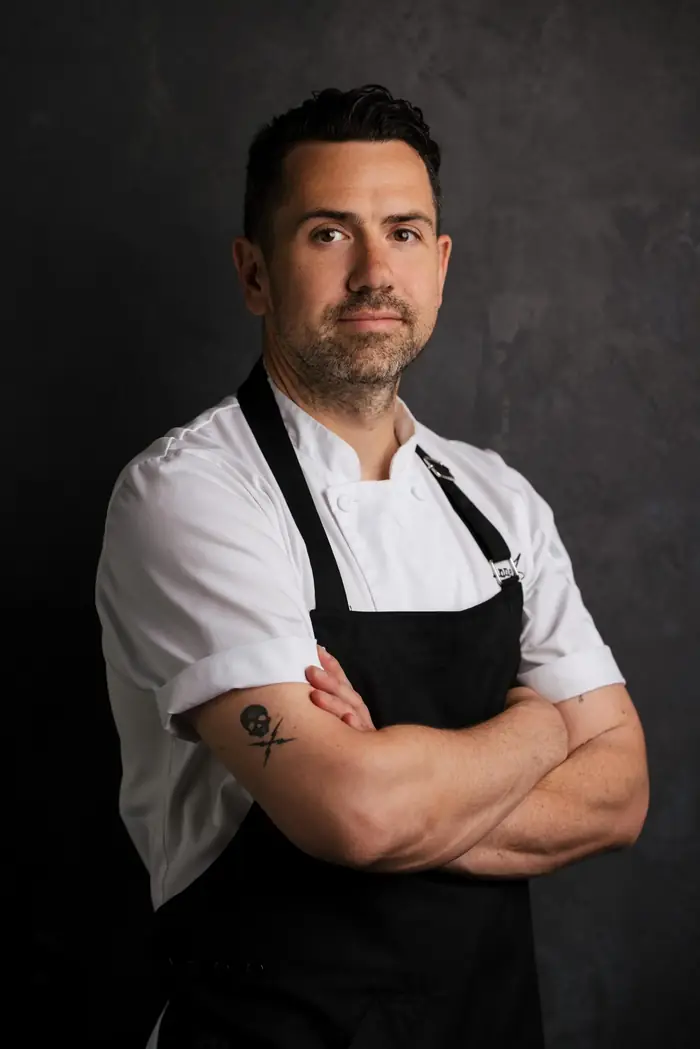 Ethan Carter in a white chef jacket and black apron